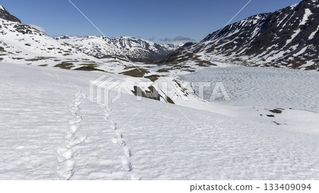 Exploring the serene snowy landscape of Leirvassbu in Jotunheimen National Park during a clear day in spring 133409094