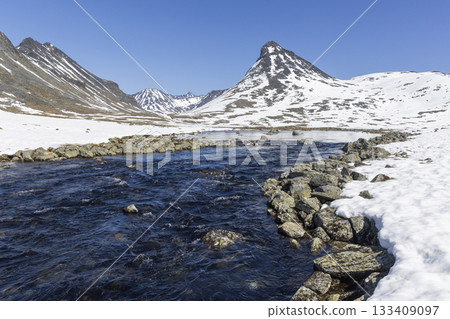 Snow-covered landscape of Leirvassbu in Leirdalen showcasing a serene river in Jotunheimen National Park 133409097