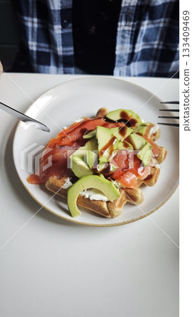 Cup of cappuccino with latte art served on a saucer next to a gourmet breakfast plate 133409469
