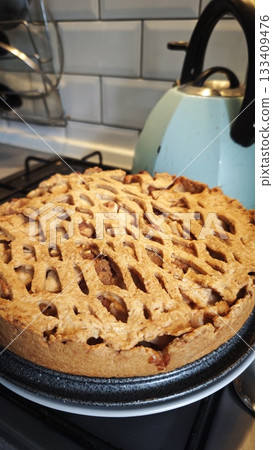 Homemade apple pie with a lattice crust cooling on the stove in a cozy kitchen setting Homemade apple pie with a lattice crust cooling on the stove in a cozy kitchen setting 133409476