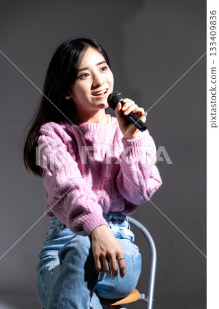 年輕女子拿著麥克風說話 年輕女子拿著麥克風說話 133409836