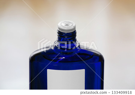 A blue translucent bottle of hair growth product with the screw cap open 133409918