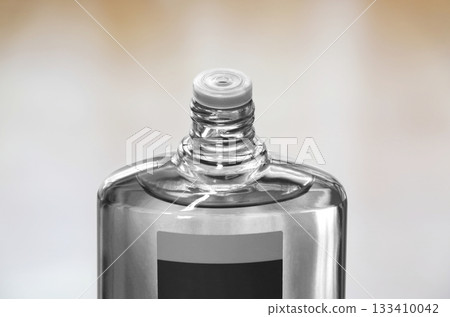 A transparent bottle of hair growth product with the screw cap open 133410042