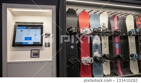 High-tech snowboard rental kiosk with touch screen and various snowboards on display in modern ski resort shop. concept of innovative rental service, winter sports gear, technology. 133410282