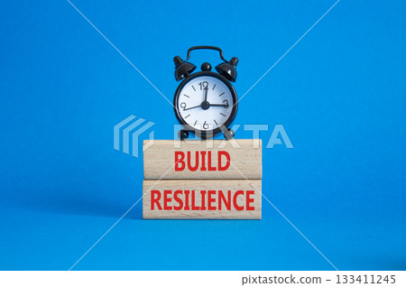 Build resilience symbol. Wooden blocks with words Build resilience. Beautiful blue background with alarm clock. Business and Build resilience concept. Copy space. 133411245