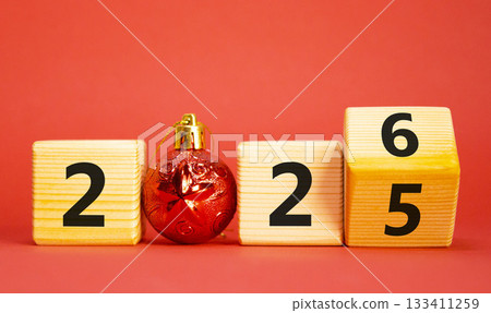 2026 New Year symbol. Businessman turns wooden cube and changes Year 2025 to 2026. Beautiful red background with christmas ball. Copy space. Business and 2026 happy new year concept 2026 New Year symbol. Businessman turns wooden cube and changes Year 2025 to 2026. Beautiful red background with christmas ball. Copy space. Business and 2026 happy new year concept 133411259