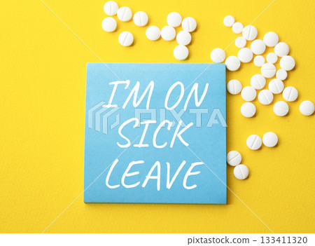 Sick leave symbol. Concept word I am on sick leave on blue note. Beautiful yellow background with pills. Medicine and I am on sick leave concept. Copy space 133411320