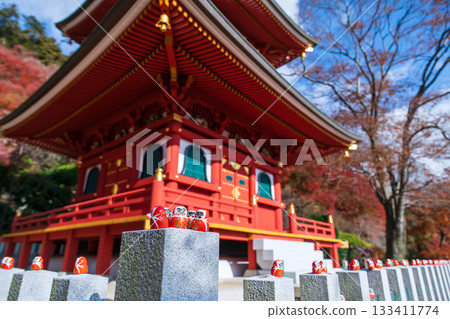 Daruma figurines on pillar by Katsuo-ji pagoda in autumn, Osaka 133411774