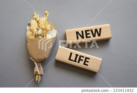 New life symbol. Concept word New life on wooden blocks. Beautiful grey background with bouquet of flowers. Business and New life concept. Copy space New life symbol. Concept word New life on wooden blocks. Beautiful grey background with bouquet of flowers. Business and New life concept. Copy space 133411932