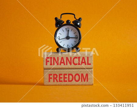 Financial freedom symbol. Wooden blocks with words Financial freedom. Beautiful orange background with alarm clock. Business and Financial freedom concept. Copy space. Financial freedom symbol. Wooden blocks with words Financial freedom. Beautiful orange background with alarm clock. Business and Financial freedom concept. Copy space. 133411951
