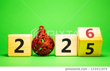 2026 New Year symbol. Businessman turns wooden cube and changes Year 2025 to 2026. Beautiful green background with christmas ball. Copy space. Business and 2026 happy new year concept 2026 New Year symbol. Businessman turns wooden cube and changes Year 2025 to 2026. Beautiful green background with christmas ball. Copy space. Business and 2026 happy new year concept 133411974