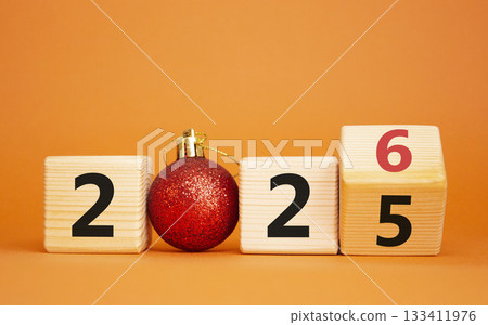 2026 New Year symbol. Businessman turns wooden cube and changes Year 2025 to 2026. Beautiful orange background with christmas ball. Copy space. Business and 2026 happy new year concept 2026 New Year symbol. Businessman turns wooden cube and changes Year 2025 to 2026. Beautiful orange background with christmas ball. Copy space. Business and 2026 happy new year concept 133411976