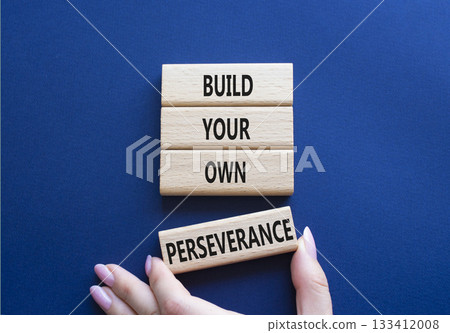 Perseverance symbol. Wooden blocks with words Build your own Perseverance. Businessman hand. Beautiful deep blue background. Business and Build your own Perseverance concept. Copy space. 133412008