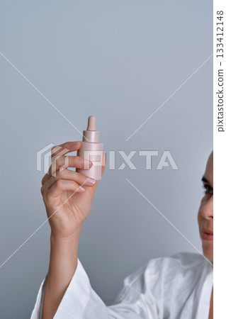Woman holding skincare serum dropper bottle Woman holding skincare serum dropper bottle 133412148