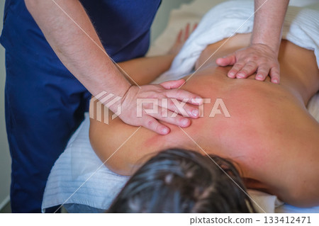 A woman enjoys a soothing back massage from a skilled therapist using oil for relaxation and lymphatic drainage in a spa salon. 133412471