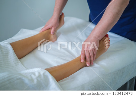 A woman enjoys a soothing calf massage at a spa salon, enhancing her wellness with a skilled therapist's touch. A woman enjoys a soothing calf massage at a spa salon, enhancing her wellness with a skilled therapist's touch. 133412473