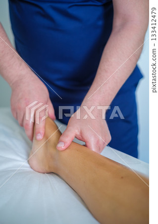 A woman enjoys a soothing foot and leg massage at a spa, where an expert therapist uses oil for relaxation and lymphatic drainage. 133412479