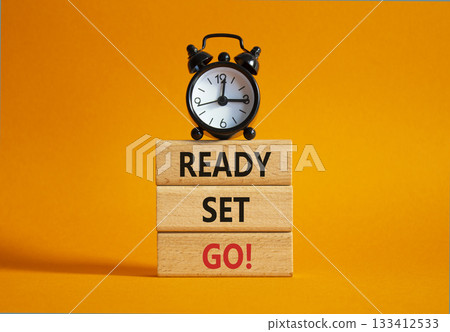 Ready Set Go symbol. Concept words Ready Set Go on wooden blocks. Beautiful orange background with alarm clock. Business and Ready Set Go concept. Copy space. 133412533