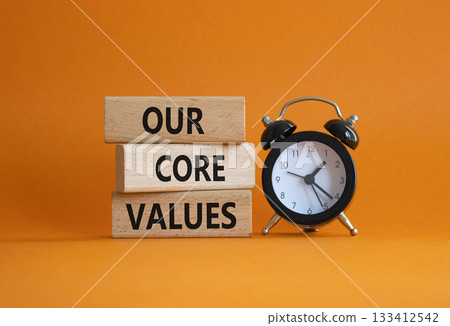 Our core values symbol. Concept words Our core values on wooden blocks. Beautiful orange background with alarm clock. Business and Our core values concept. Copy space. 133412542