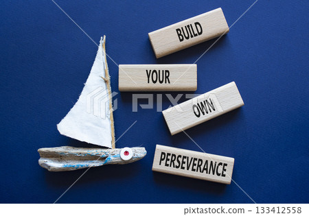 Perseverance symbol. Wooden blocks with words Build your own Perseverance. Businessman hand. Beautiful deep blue background with boat. Business and Build your own Perseverance concept. Copy space. 133412558