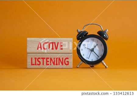 Listen actively symbol. Wooden blocks with words Listen actively. Beautiful orange background with alarm clock. Business and Active listening concept. Copy space. 133412613