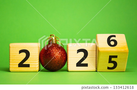 2026 New Year symbol. Businessman turns wooden cube and changes Year 2025 to 2026. Beautiful green background with christmas ball. Copy space. Business and 2026 happy new year concept 2026 New Year symbol. Businessman turns wooden cube and changes Year 2025 to 2026. Beautiful green background with christmas ball. Copy space. Business and 2026 happy new year concept 133412618