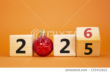 2026 New Year symbol. Businessman turns wooden cube and changes Year 2025 to 2026. Beautiful orange background with christmas ball. Copy space. Business and 2026 happy new year concept 2026 New Year symbol. Businessman turns wooden cube and changes Year 2025 to 2026. Beautiful orange background with christmas ball. Copy space. Business and 2026 happy new year concept 133412622