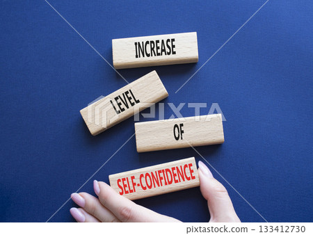 Self-confidence symbol. Wooden blocks with words Increase level of Self-confidence. Beautiful deep blue background. Businessman hand. Business concept. Copy space. 133412730