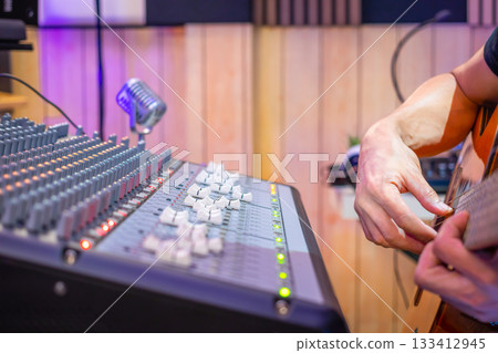 close up male musician hands playing acoustic guitar in home studio, recording concept. 133412945