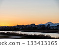 The silhouette of Mt. Fuji and the cityscape in the orange sunset sky seen from the bank of the Tama River 133413165