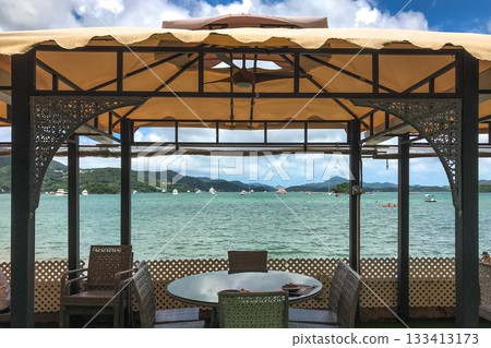 The tranquil scene features a table set for dining, with a beautiful ocean view in the background The tranquil scene features a table set for dining, with a beautiful ocean view in the background 133413173