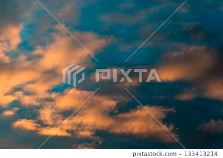 Dramatic sky with orange and blue clouds at sunset. The vibrant colors of the clouds create a stunning and captivating display in the sky. Atmospheric evening skyline. Abstract moody twilight scene. 133413214