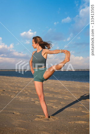 Woman yoga practice at the beach in Utthita Hasta Padangusthasana Extended Hand-to-Big-Toe Pose pose 133413505