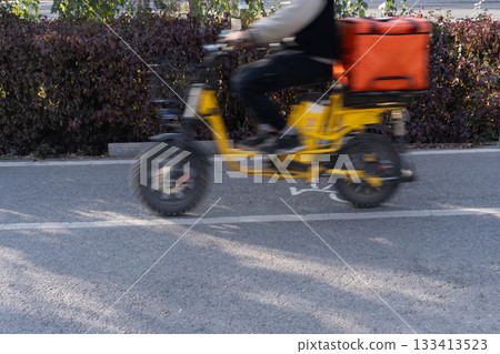 Food delivery rider on yellow electric bike 133413523