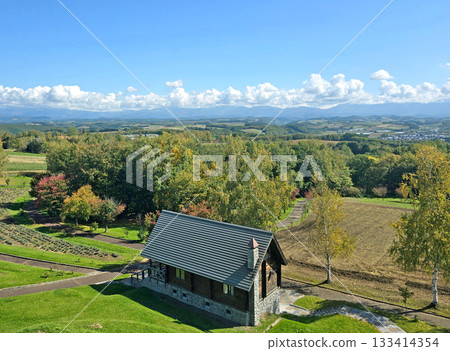 This beautiful landscape showcases a cabin nestled in nature, with rolling hills and a stunning mountain backdrop This beautiful landscape showcases a cabin nestled in nature, with rolling hills and a stunning mountain backdrop 133414354