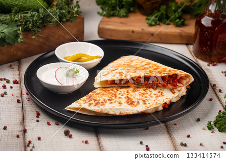 Grilled chicken quesadilla on black plate serving Grilled chicken quesadilla on black plate serving 133414574