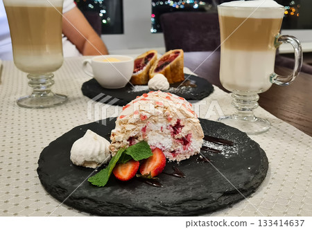 A plate of cake with strawberries and whipped cream sits on a black plate A plate of cake with strawberries and whipped cream sits on a black plate 133414637