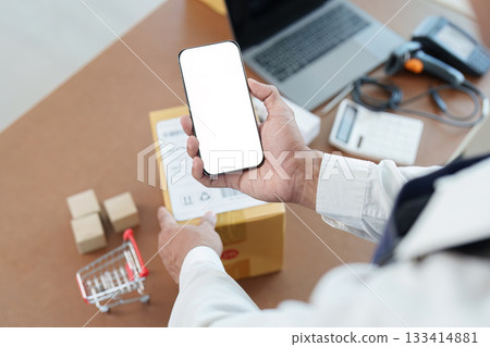 Delivery Confirmation. Worker holding smartphone and package in logistics office. Delivery Confirmation. Worker holding smartphone and package in logistics office. 133414881