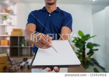 Logistics management. Worker presenting clipboard for package verification in office. Logistics management. Worker presenting clipboard for package verification in office. 133414918