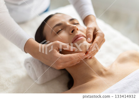 Beautiful young woman receiving gentle chin massage at spa Beautiful young woman receiving gentle chin massage at spa 133414932