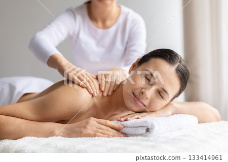 Young woman receiving gentle upper back massage at spa 133414961