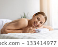 Young female smiling gently while lying on spa bed before massage 133414977