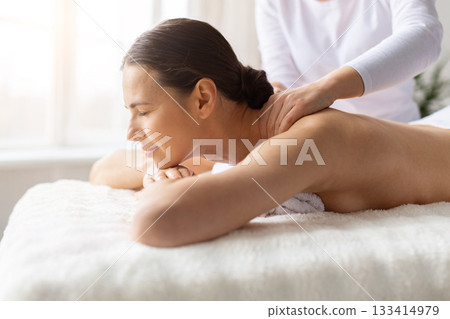 Young female receiving shoulder and upper back massage at spa 133414979