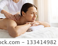 Female enjoying body massage at spa, eyes closed and resting on towel 133414982