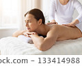 Back massage session with young woman relaxing on a spa bed 133414988