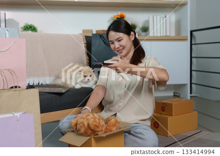 Excited Shopping Moment. Woman enjoying online shopping with her cat beside her. Excited Shopping Moment. Woman enjoying online shopping with her cat beside her. 133414994