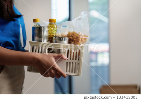Food Donation Collection. Volunteer carrying food items for community support. 133415005