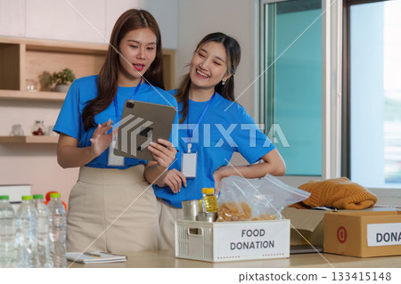 Food Donation Awareness. Volunteers discussing food donation efforts using a tablet. Food Donation Awareness. Volunteers discussing food donation efforts using a tablet. 133415148