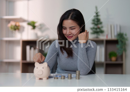 Savings: Woman Depositing Coins into Piggy Bank with Joy Savings: Woman Depositing Coins into Piggy Bank with Joy 133415164