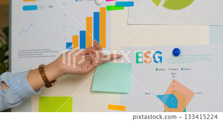 ESG Insights. Close-up of hand analyzing sustainability data on presentation board. ESG Insights. Close-up of hand analyzing sustainability data on presentation board. 133415224